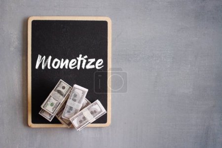 Photo for Top view stack of money and text MONETIZE with copy space for text. Content monetization concept - Royalty Free Image