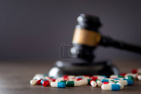 Foto de Imagen de primer plano de píldoras de medicina de colores y juez martillo en la mesa. Concepto de derecho médico. - Imagen libre de derechos