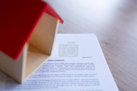 Closeup image of toy house and home financing offer letter from bank. Home ownership concept.