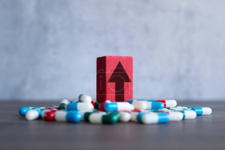 Photo for Upward-pointing arrow and a pile of colorful pills. High demand, rising costs of prescription drugs concept. - Royalty Free Image