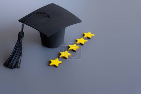 Cap de graduation à côté d'une rangée de cinq étoiles notation sur un fond gris. Espace de copie pour le texte. Meilleur concept de système éducatif.