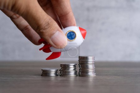 Closeup image of rocket spaceship and coins. Business startup, launch and boost concept.