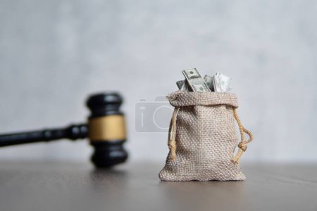 Closeup image bag of money and judge gavel. Lawsuit, auction, bribe and penalty concept.