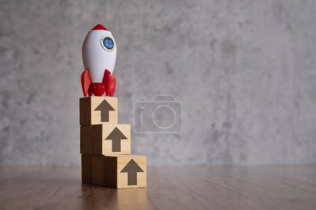 A stack of wooden blocks with arrows pointing upwards and rocket. Copy space for text.