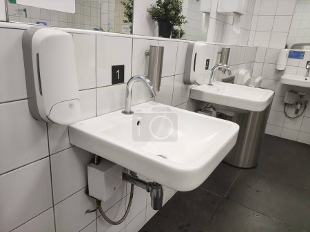 Modern bathroom sink and touchless faucet in public toilet and restroom.