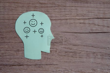 A green paper cut-out of a human head with a smile face and positive icon. Copy space for text. Positive thinking concept.