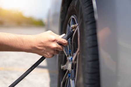 Foto de Imagen de primer plano del hombre inflando el neumático, llenando el aire en los neumáticos de su coche. - Imagen libre de derechos