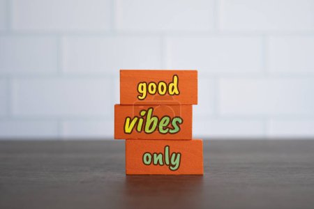 Wooden cubes with text GOOD VIBES ONLY on wooden table.
