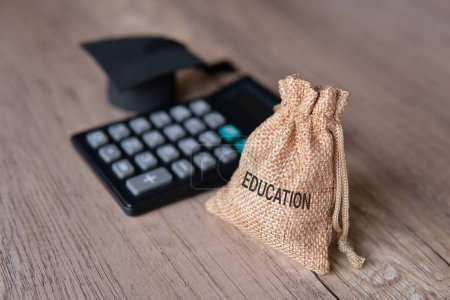 Photo for Closeup image of graduation cap, calculator and money bag with word EDUCATION. Financial concept. - Royalty Free Image