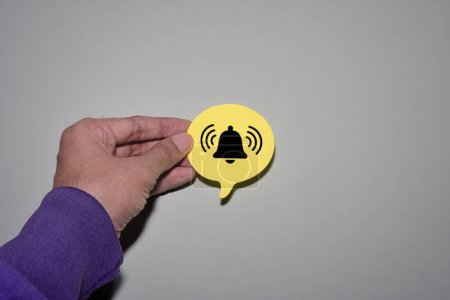 Hand holding speech bubble with ringing bell icon. Reminder, notification concept.