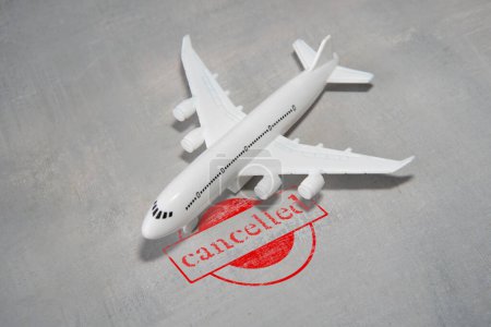 Toy airplane with a red "cancelled" stamp next to it. Flight cancellation concept.