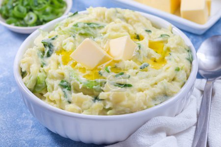 Photo for Traditional Irish dish Colcannon or mashed potato with green cabbage and butter, served in white bowl, spring onion and butter on light blue concrete background, St Patrick day food, horizontal - Royalty Free Image