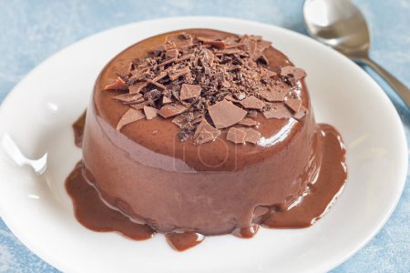Téléchargez les photos : Dessert au chocolat Panna Cotta sur une assiette blanche, panneau en bois avec chocolat cassé sur un fond, horizontal, gros plan - en image libre de droit