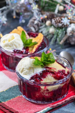 Foto de Delicioso zapatero Berry en ramekin de vidrio con helado, decoración navideña sobre fondo, vertical - Imagen libre de derechos