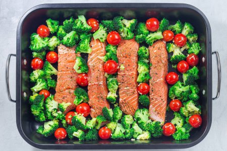 Raw salmon fillet with broccoli and tomato on a frying tray, ready to bake, horizontal, top view