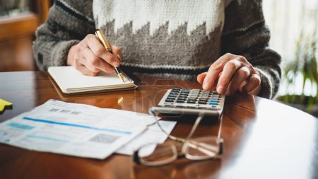 Femme tapant sur une calculatrice, calculant les factures de services publics