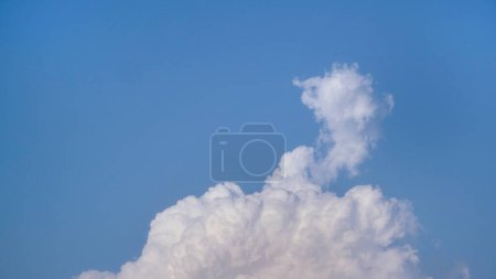 Weiße flauschige Wolken offen für Fantasie Ideenform gegen strahlend blauen Himmel für Hintergrund mit Kopierraum, grafische Ressource, Wolkenbewegung vom Wind