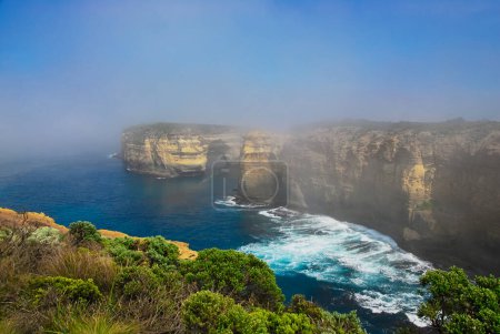 As the morning fog dissipates, the eroded limestone cliffs of the rugged south coast of Australia come into view.