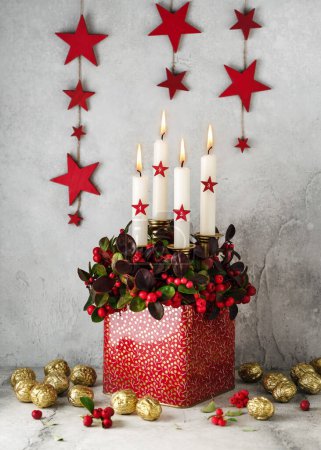 Téléchargez les photos : Plante de damier rouge avec quatre bougies blanches et des étoiles en bois dans un chaudron décoré de noix d'or. Décoration maison pour Noël. (Gaultheria procumbens) - en image libre de droit