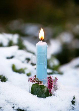 Téléchargez les photos : Bougeoir de Noël fait à la main en glace, branches de fleur de calluna rose avec bougie bleue brûlante dans le garen recouvert de neige. Concept de décoration extérieure d'hiver - en image libre de droit