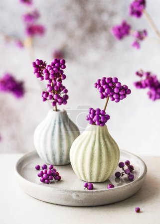 Wunderschönes floristisches Arrangement mit lila Schönheit Beerenzweigen in Mini-Keramikvasen. Romantisches minimales Blumenstillleben. Kopierraum (Callicarpa bodinieri)
