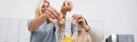 Téléchargez les photos : Vue à angle bas des amis flous mettant des fruits dans le mélangeur, bannière - en image libre de droit