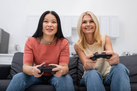 Photo for KYIV, UKRAINE - DECEMBER 2, 2021: Interracial women playing video game while spending time at home - Royalty Free Image