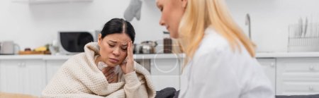 Sick asian woman suffering from headache near blurred doctor at home, banner 