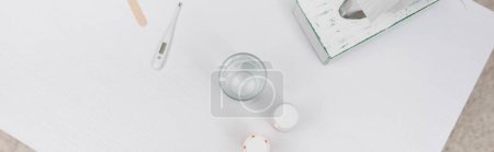 Top view of electronic thermometer near glass of water and pills on table at home, banner  Poster 626931784