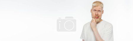 zamyślony albinos mężczyzna w t-shirt dotykając brody podczas myślenia na białym, baner