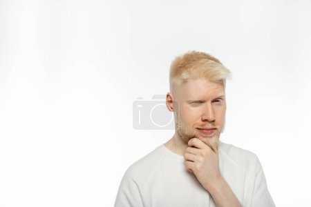 hombre albino pensativo tocando la barba mientras piensa en el fondo blanco
