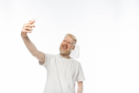 Foto de Hombre albino feliz en camiseta tomando selfie en teléfono inteligente sobre fondo blanco - Imagen libre de derechos