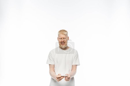 hombre albino feliz en camiseta con teléfono inteligente sobre fondo blanco 