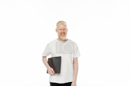 cheerful albino freelancer man in t-shirt holding laptop isolated on white