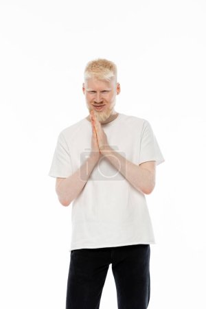 cheerful albino man in t-shirt standing with praying hands isolated on white 