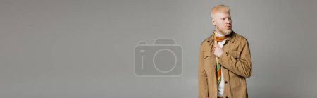 bearded albino man in stylish shirt jacket and silk scarf posing isolated on grey, banner