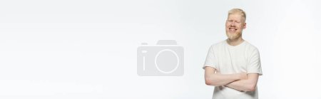 brodatego albinosa w t-shircie uśmiechającego się i stojącego z skrzyżowanymi ramionami odizolowanego na białym, chorągwiu