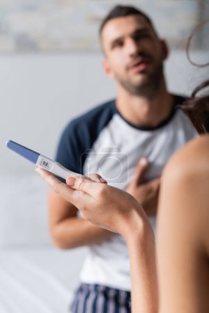 Téléchargez les photos : Woman holding negative pregnancy test near blurred boyfriend at home - en image libre de droit