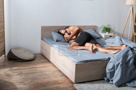 Téléchargez les photos : Passionate man kissing sensual girlfriend on bed in morning - en image libre de droit
