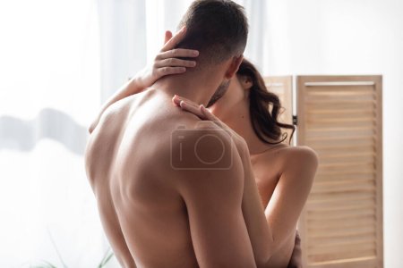 Téléchargez les photos : Muscular man kissing naked girlfriend at home - en image libre de droit