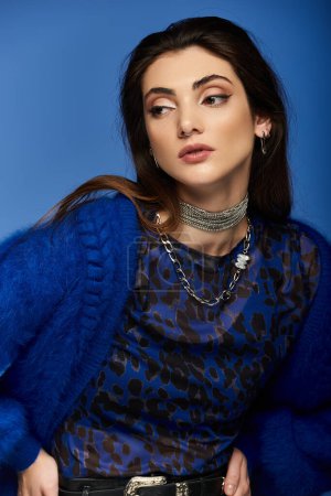 A young woman wearing a blue cardigan and a leopard print shirt.