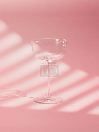 Ein elegantes Bild eines leeren Glaspokals auf einem leuchtend rosa Hintergrund. Die minimalistische Komposition betont Einfachheit und Raffinesse, ideal für Drink-Themen, Stil und modernes Design.