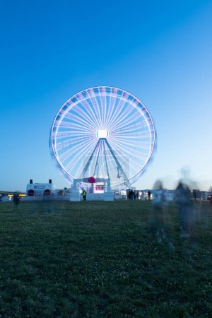 Photo for A stunning long exposure shot of a brightly lit Ferris wheel at Rock in Rio Lisboa 2024. The vibrant lights and motion blur create a mesmerizing effect, capturing the festive atmosphere of the night. - Royalty Free Image