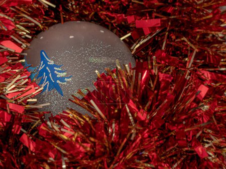 Foto de Bola festiva de Navidad enclavada en vibrantes decoraciones de oropel rojo - Imagen libre de derechos