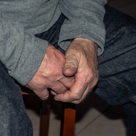 Elderly caucasian person's hands making adjustments to the fit of worn blue jeans