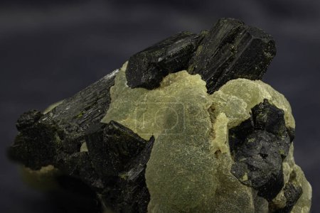 Cluster von Perzeptkristallen, deren blassgrüne Transluzenz ein Markenzeichen dieses einzigartigen afrikanischen Minerals ist, dem krasse schwarze Mineralkontraste gegenübergestellt werden