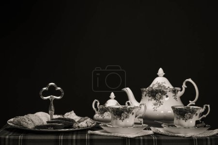 Tasse Tee mit Zucker und Keksen auf dem schwarzen Tisch