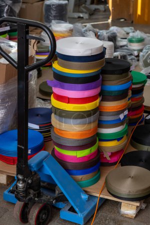 Téléchargez les photos : Piles de bandes textiles colorées sur le matériel de transport sur l'usine - en image libre de droit