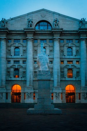 Téléchargez les photos : Milan, Italie - Septembre 2023 : Statue en marbre de Maurizio Cattelan devant la Bourse italienne au centre de la Piazza Affari de Milan, heure bleue - en image libre de droit