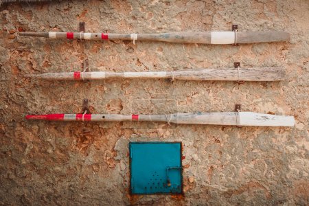 Marzameni, Sicilia, Italia - 16 de marzo de 2022: Tres antiguos remos de madera colgados en una pared del antiguo pueblo pesquero siciliano